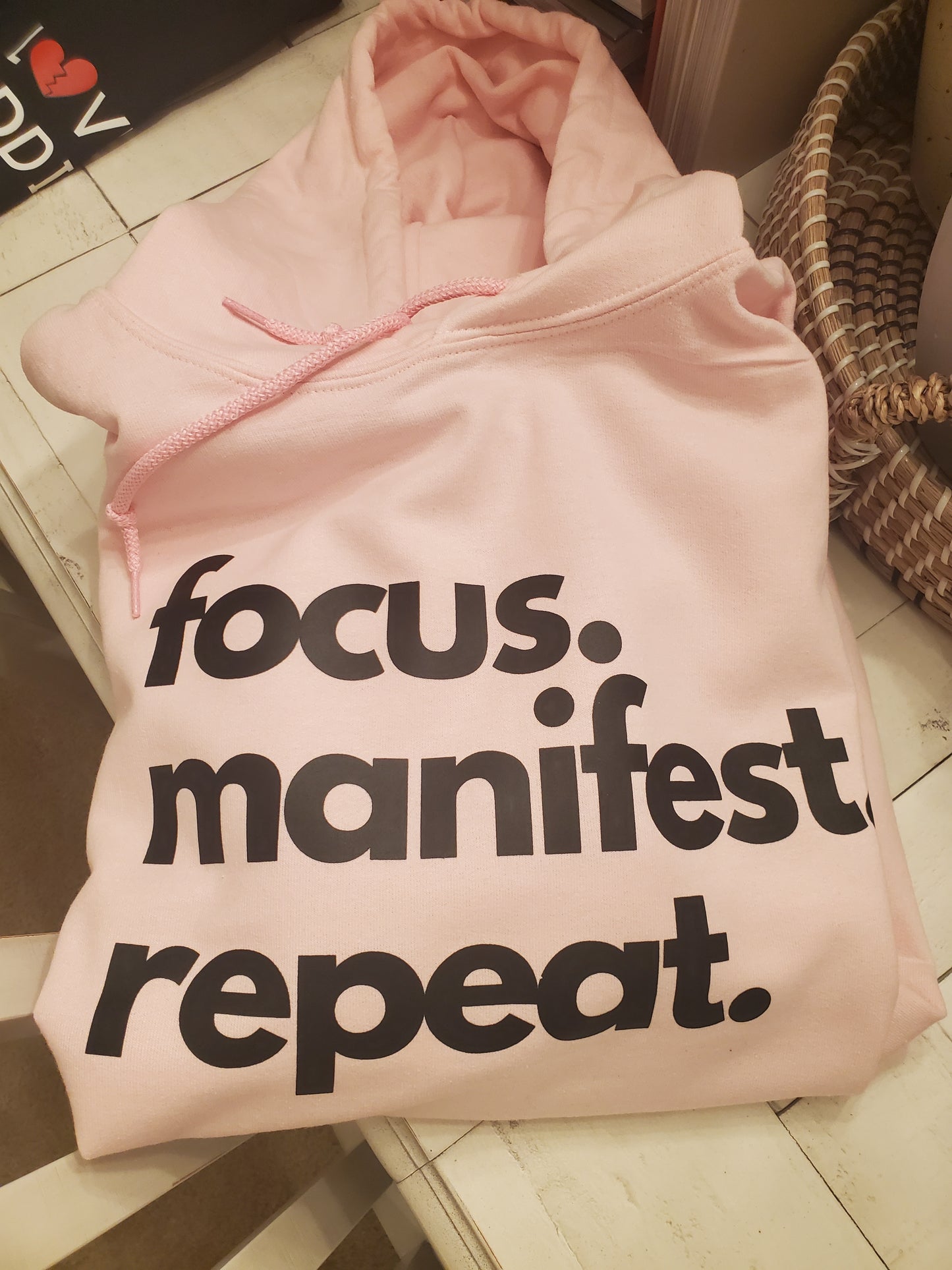 Pink hoodie black letters focus manifest repeat